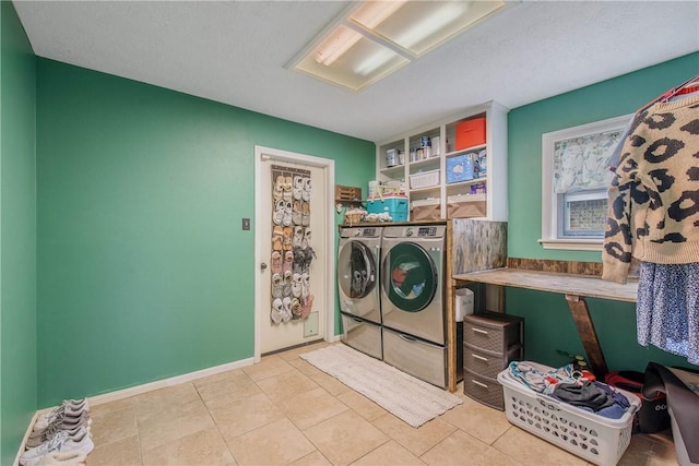 laundry area with laundry area, washing machine and dryer, baseboards, and light tile patterned flooring