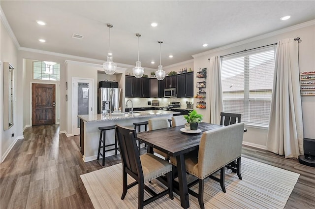 dining room featuring hardwood / wood-style flooring, ornamental molding, and sink