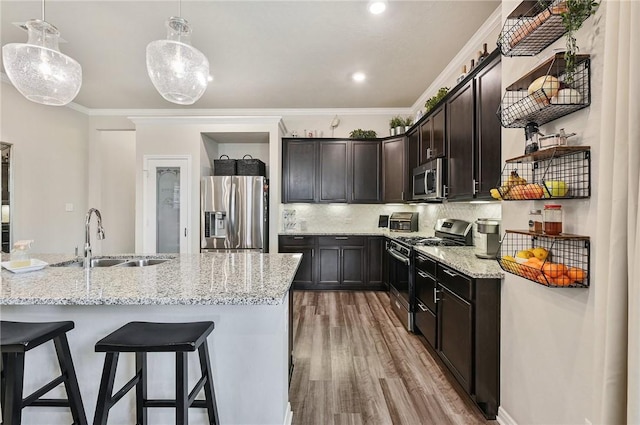 kitchen featuring pendant lighting, sink, ornamental molding, appliances with stainless steel finishes, and wood-type flooring