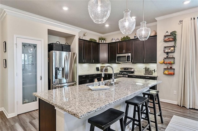 kitchen with dark brown cabinetry, sink, an island with sink, and stainless steel appliances