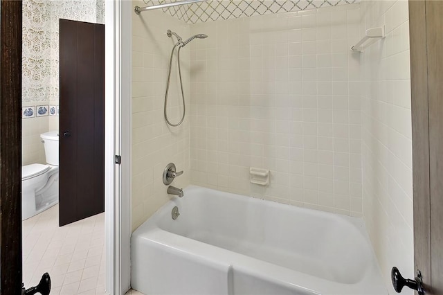 bathroom featuring tile patterned floors, tile walls, tiled shower / bath combo, and toilet