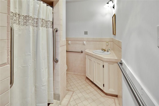 bathroom with tile patterned floors, vanity, tile walls, and walk in shower