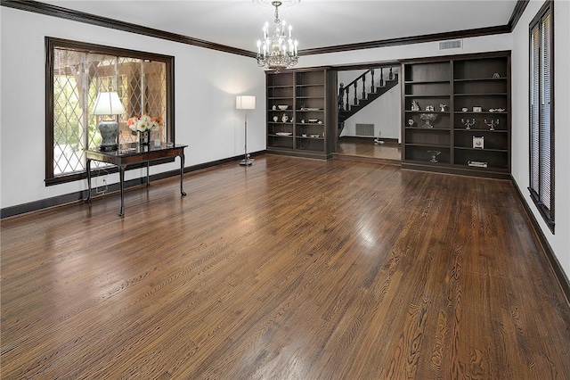 empty room with hardwood / wood-style floors, crown molding, and an inviting chandelier