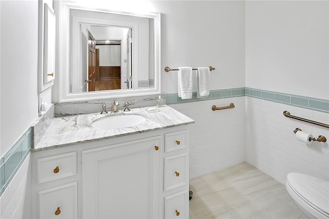 bathroom featuring vanity, toilet, and tile walls