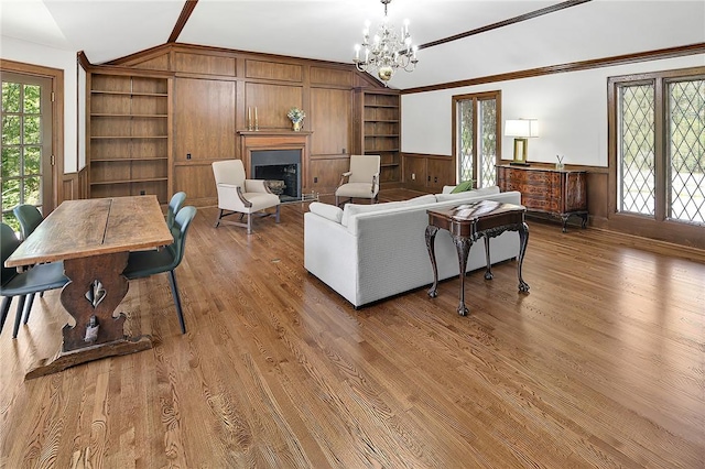 living room featuring wood walls, hardwood / wood-style floors, a chandelier, and vaulted ceiling