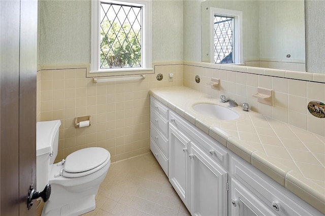 bathroom featuring tile patterned flooring, vanity, toilet, and tile walls