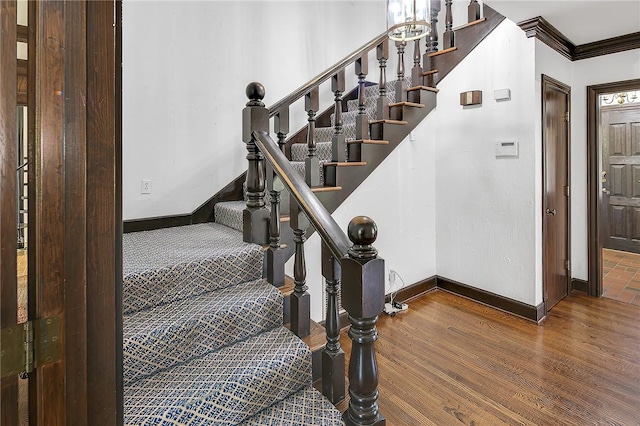 staircase with hardwood / wood-style floors and crown molding