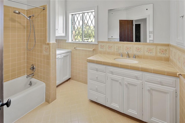 bathroom with tile patterned floors, vanity, tile walls, and tiled shower / bath