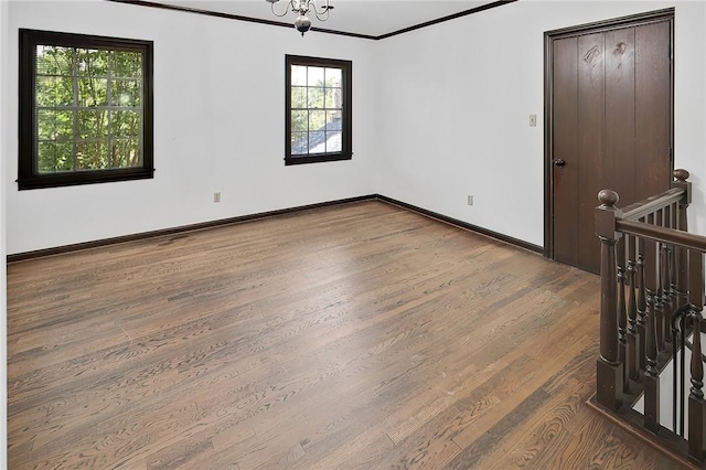 unfurnished room with a chandelier, wood-type flooring, and ornamental molding