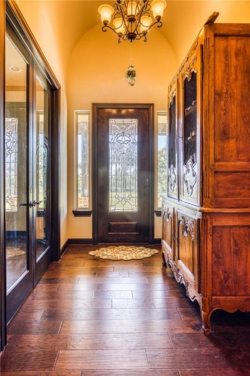 foyer featuring dark hardwood / wood-style floors, an inviting chandelier, french doors, and vaulted ceiling