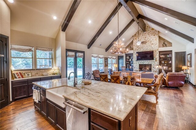 kitchen with appliances with stainless steel finishes, premium range hood, high vaulted ceiling, and a kitchen island with sink