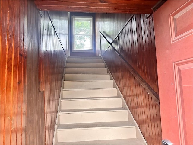 stairway featuring wood walls