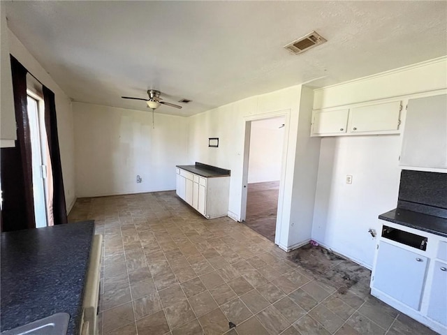 kitchen featuring white cabinets, dark countertops, visible vents, and a ceiling fan