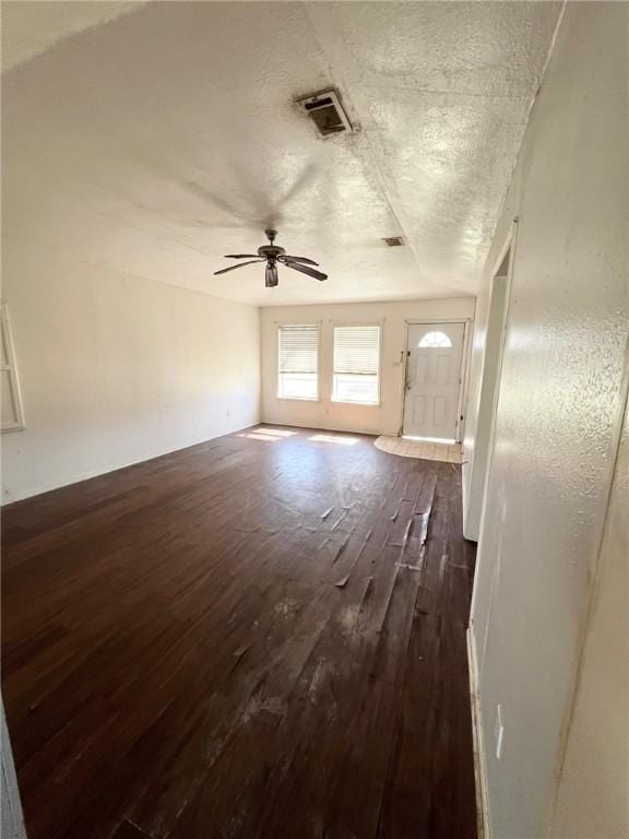 unfurnished living room with dark wood-style floors, a ceiling fan, visible vents, and a textured ceiling