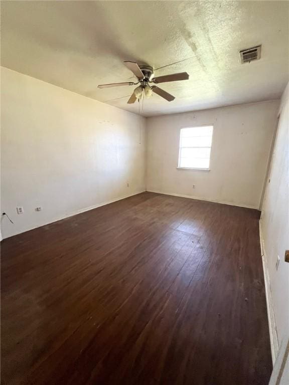 spare room featuring dark wood-style floors, ceiling fan, a textured ceiling, and visible vents