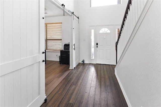 entryway with a barn door and dark hardwood / wood-style floors