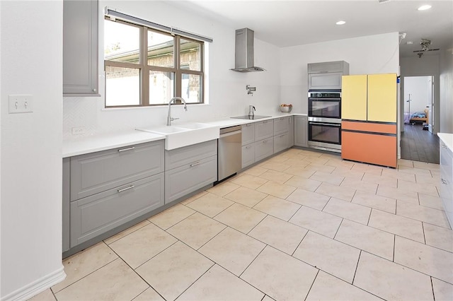 kitchen featuring appliances with stainless steel finishes, light wood-type flooring, gray cabinetry, wall chimney exhaust hood, and sink