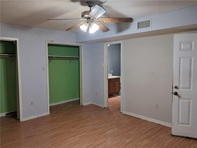 1202 Cheyenne Dr, Brenham, TX 77833 - unfurnished bedroom featuring two closets, light wood finished floors, and a ceiling fan