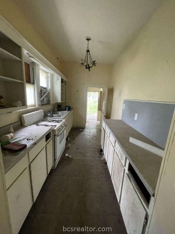 kitchen featuring sink, white gas range oven, hanging light fixtures, and an inviting chandelier