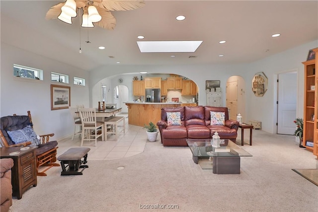 living room with ceiling fan, light colored carpet, and a skylight