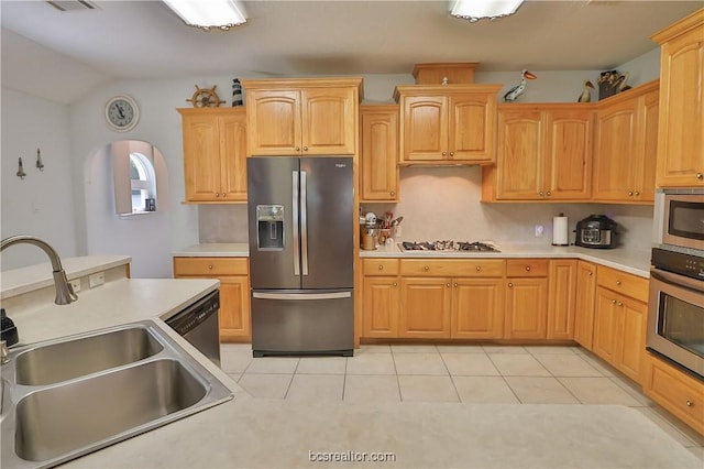 kitchen with appliances with stainless steel finishes, light brown cabinetry, sink, light tile patterned floors, and lofted ceiling