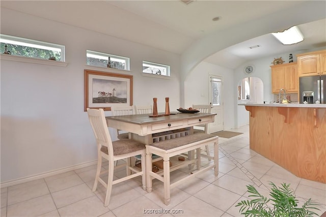 dining room with sink, light tile patterned floors, and vaulted ceiling