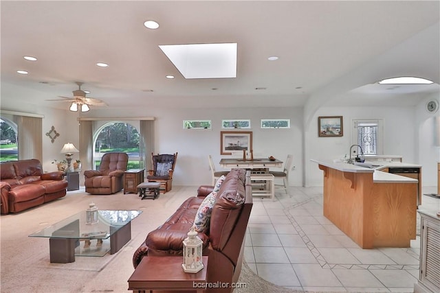 living room with a skylight, sink, light tile patterned flooring, and a healthy amount of sunlight