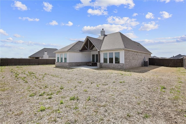 rear view of house featuring a fenced backyard, central AC, brick siding, a chimney, and a patio area