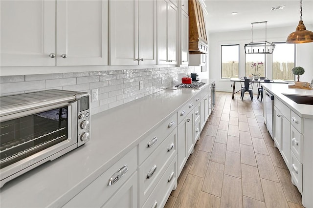 kitchen featuring visible vents, decorative light fixtures, light countertops, white cabinetry, and backsplash