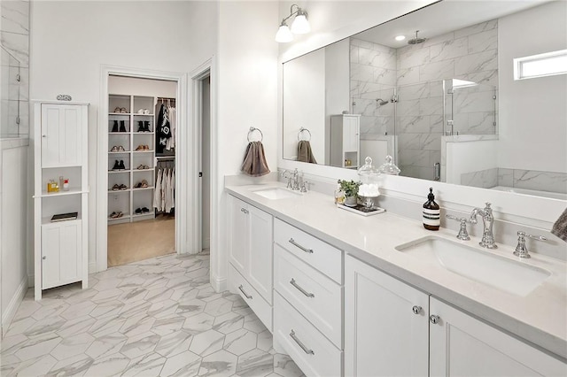 bathroom with double vanity, a marble finish shower, and a sink