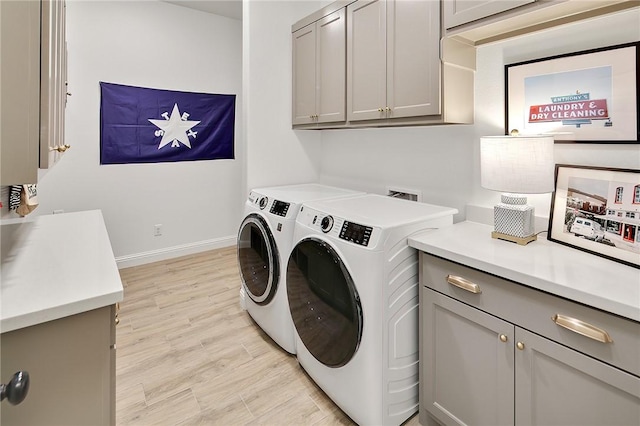 laundry room with washing machine and dryer, baseboards, cabinet space, and light wood finished floors