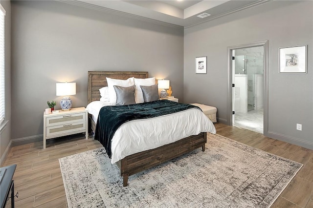 bedroom with crown molding, visible vents, ensuite bathroom, wood finished floors, and baseboards