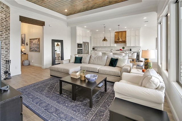 living area with light wood-type flooring, a tray ceiling, wooden ceiling, and baseboards