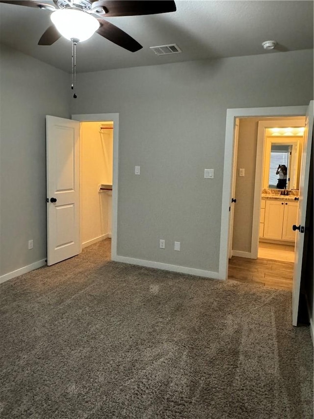 unfurnished bedroom featuring carpet, a closet, a spacious closet, and ceiling fan