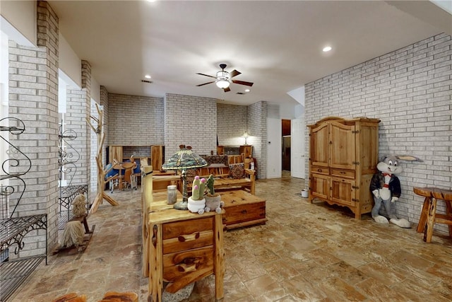 living room featuring ceiling fan and brick wall