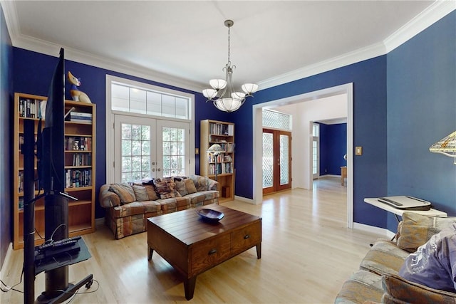 living room featuring a chandelier, french doors, light hardwood / wood-style flooring, and ornamental molding