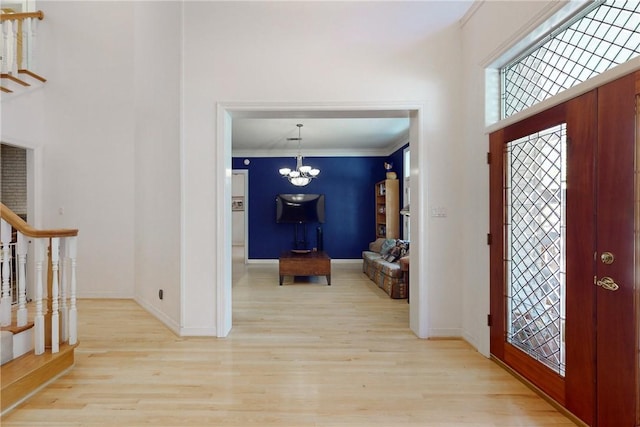 foyer entrance featuring a chandelier, crown molding, and light hardwood / wood-style flooring