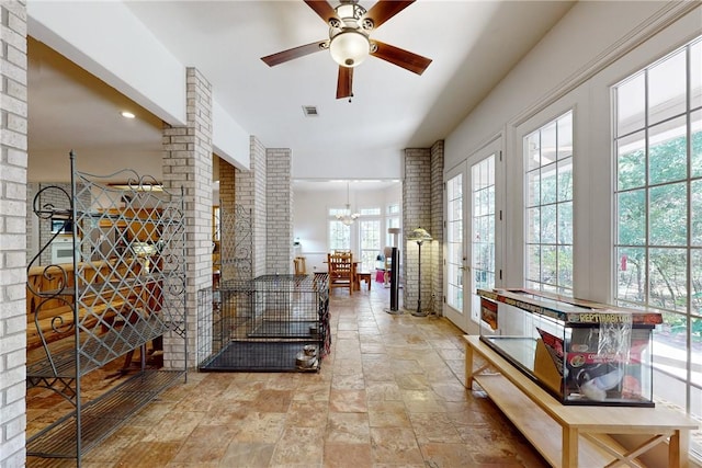 wine cellar featuring french doors and ceiling fan with notable chandelier