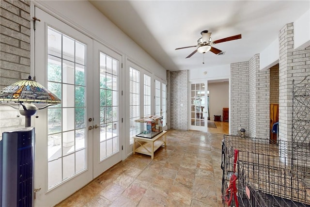 doorway featuring ceiling fan, french doors, and brick wall