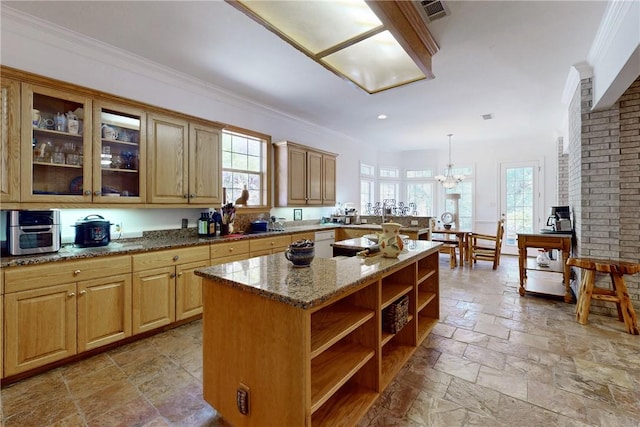 kitchen with light stone countertops, a center island, decorative light fixtures, and plenty of natural light