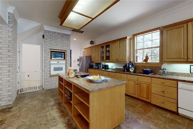 kitchen with light stone countertops, brick wall, white appliances, a kitchen island, and ornamental molding