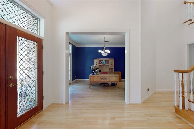 foyer featuring crown molding, light wood-type flooring, and a notable chandelier