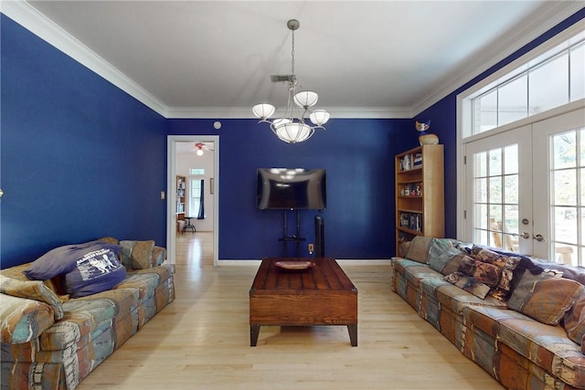 living room with crown molding, french doors, a notable chandelier, and light wood-type flooring