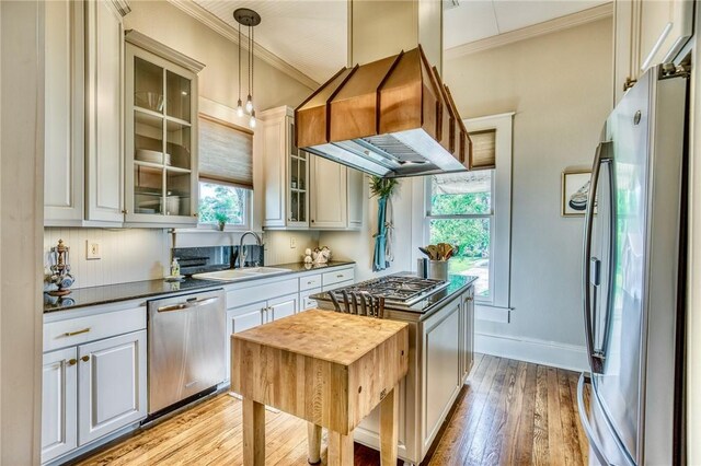 402 Ross St, Brenham, TX 77833 - kitchen featuring stainless steel appliances, a sink, ornamental molding, light wood finished floors, and dark countertops