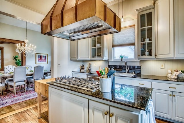 402 Ross St, Brenham, TX 77833 - kitchen featuring range hood, light wood-style floors, a sink, a chandelier, and stainless steel gas cooktop
