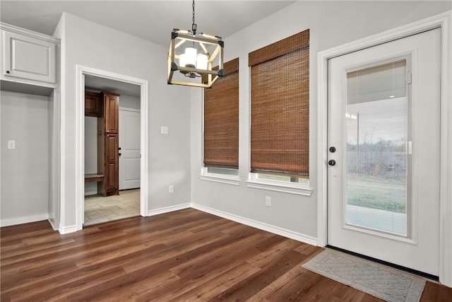 unfurnished dining area featuring a notable chandelier and dark hardwood / wood-style floors