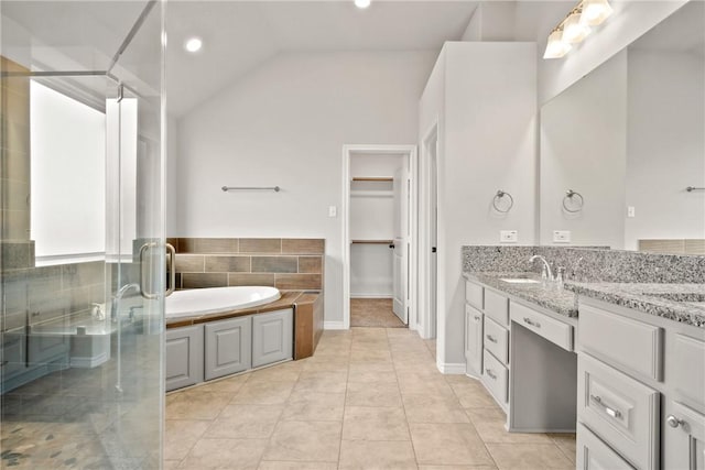 bathroom with tile patterned floors, vaulted ceiling, plus walk in shower, and vanity