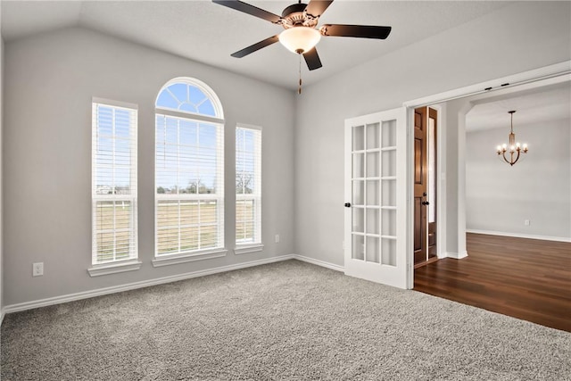 carpeted spare room featuring ceiling fan with notable chandelier and lofted ceiling