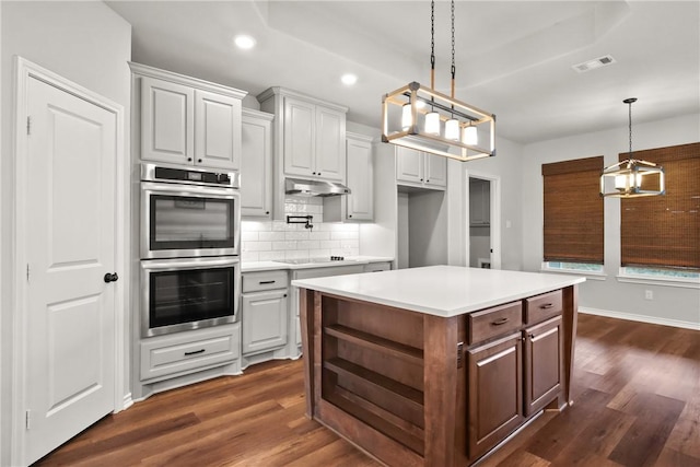 kitchen with double oven, white cabinets, hanging light fixtures, and a center island