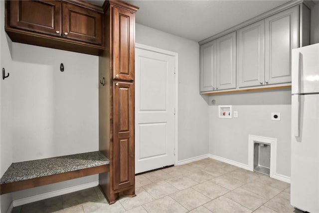 clothes washing area with electric dryer hookup, cabinets, light tile patterned floors, and washer hookup